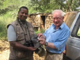 Yaya, your guide, smiling with binoculars around his neck
