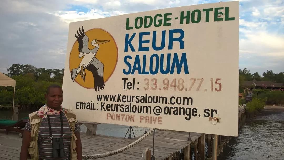A guide beside the Lodge-Hotel Keur Saloum sign on the jetty at Toubakouta